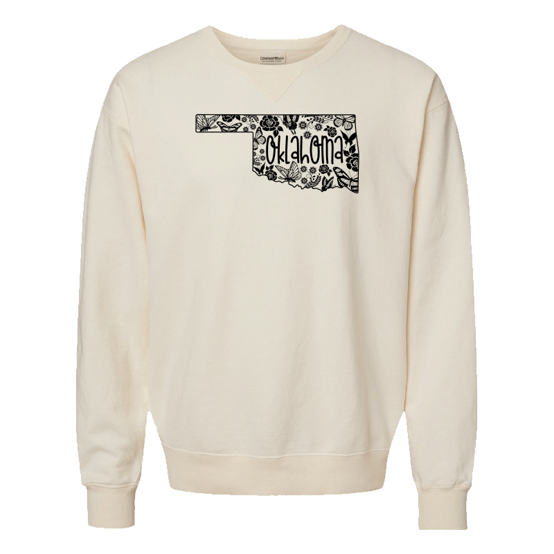 Parchment-colored sweatshirt. Graphic design: various butterflies and flowers making the outline of the state of Oklahoma. Inset text displays the state name.